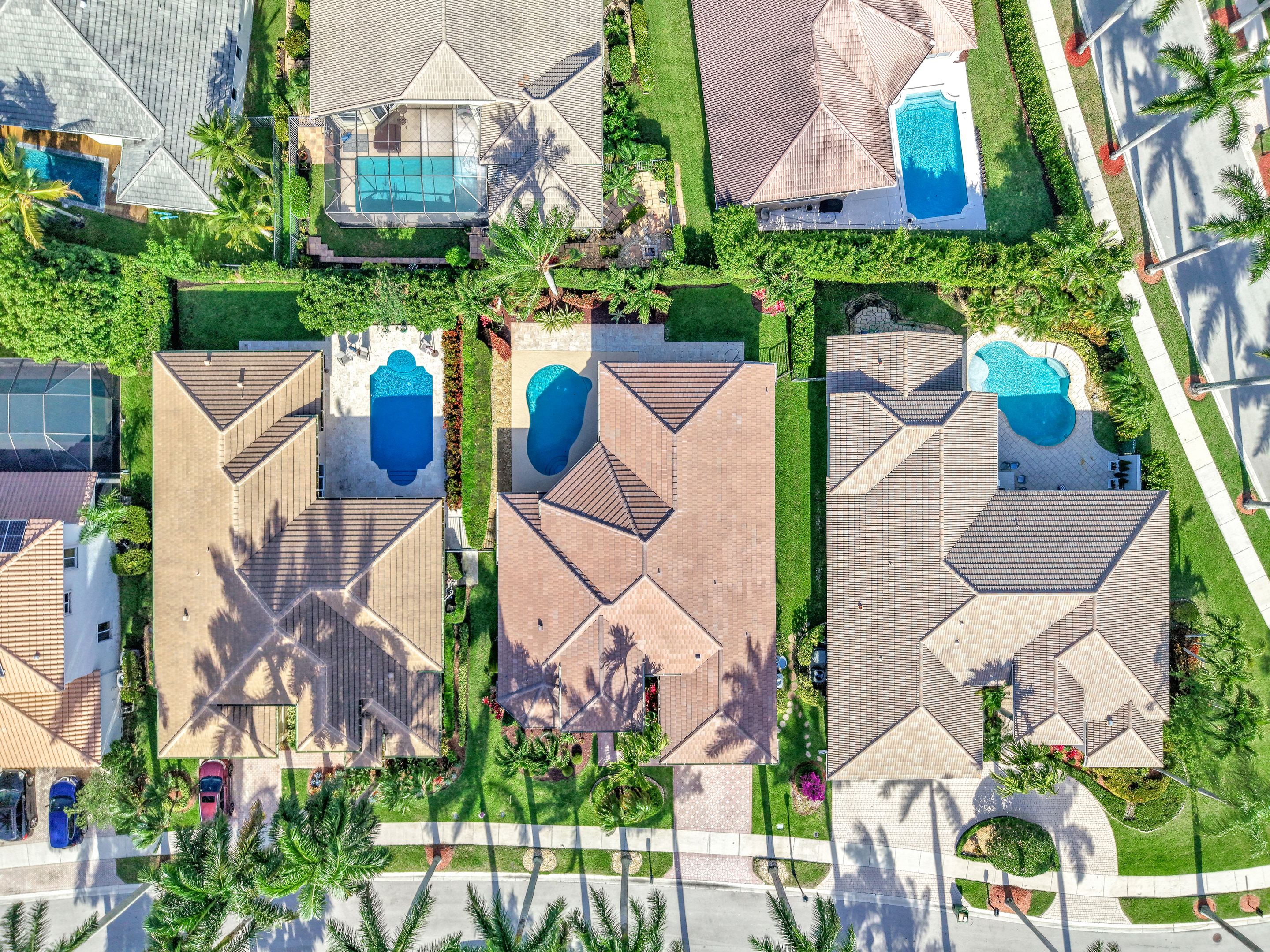 Aerial view of a South Florida street of homes with screened backyard pools