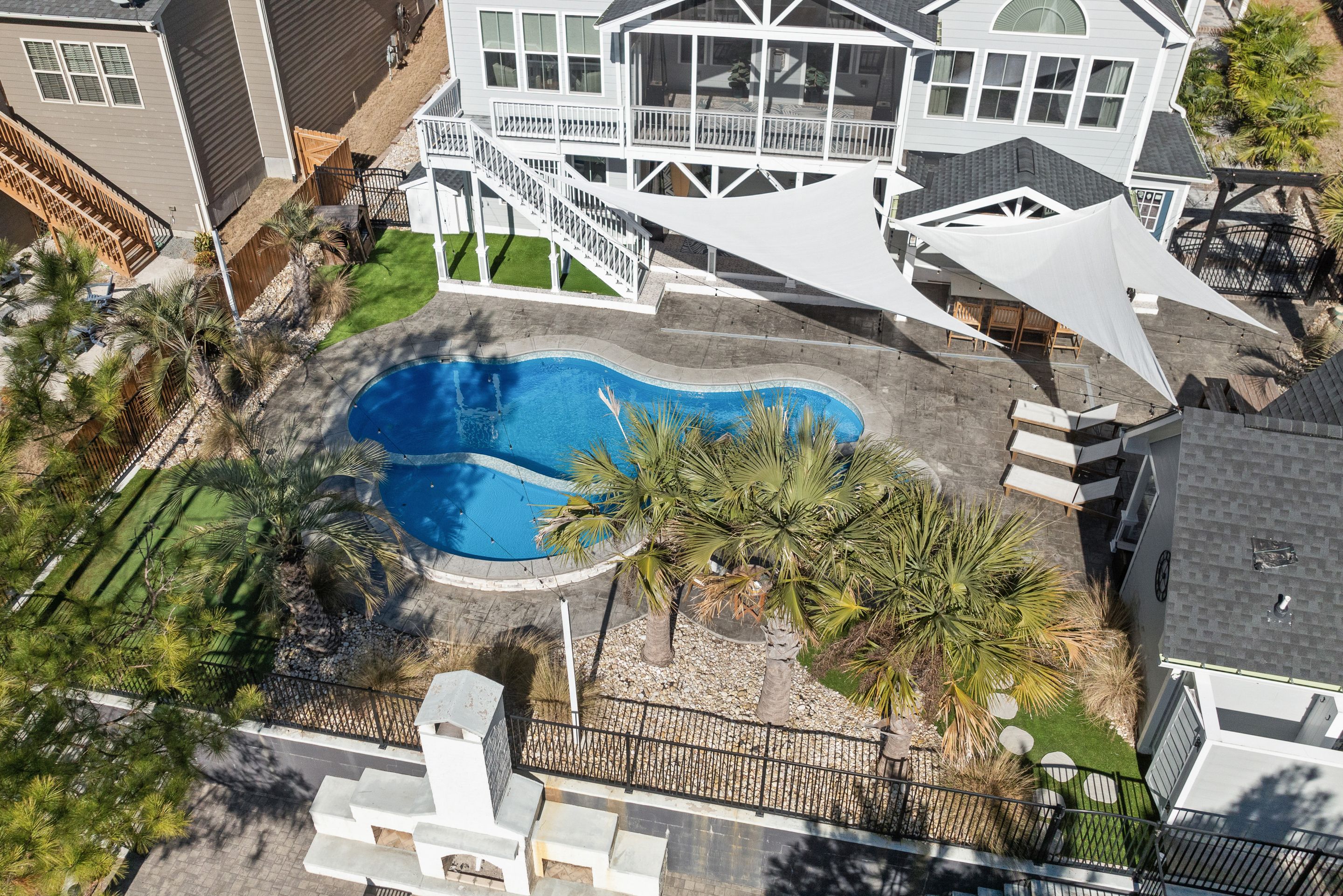 Aerial view of a backyard with a freeform pool, paver deck and fan palms