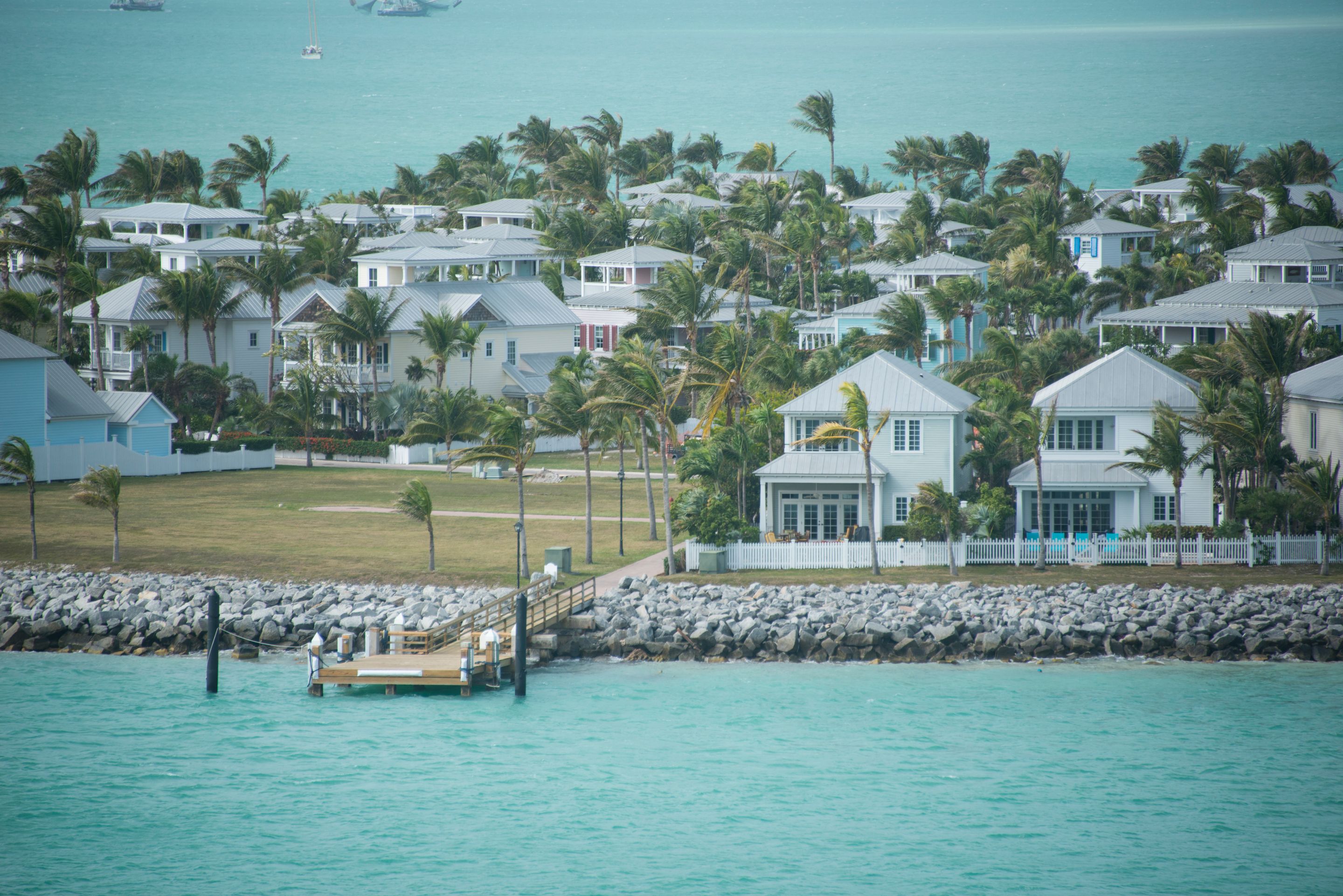 Pastel waterfront cottages with palm trees beside turquoise water