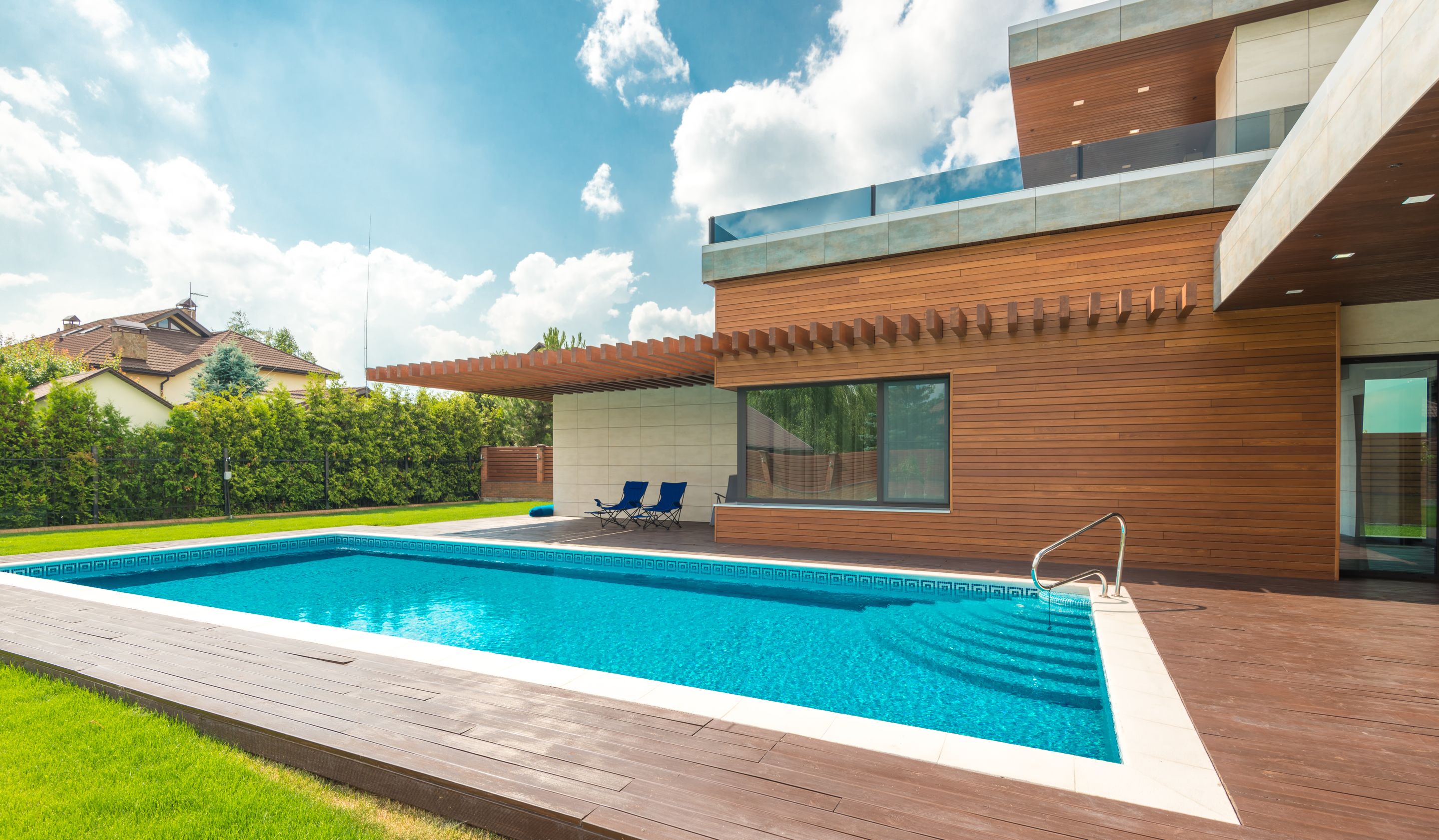 A house with a rectangular swimming pool and a wood deck in the backyard