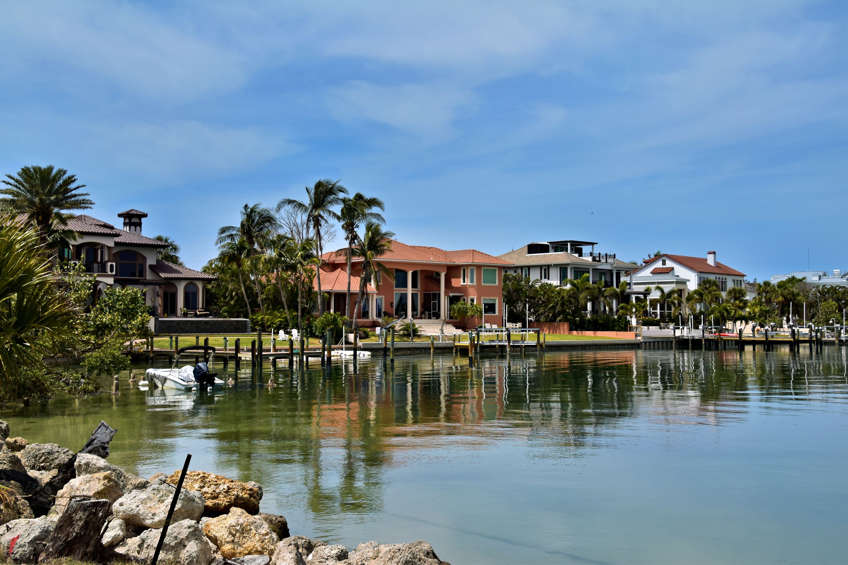 Waterfront homes with terracotta roofs across a canal, with a small boat