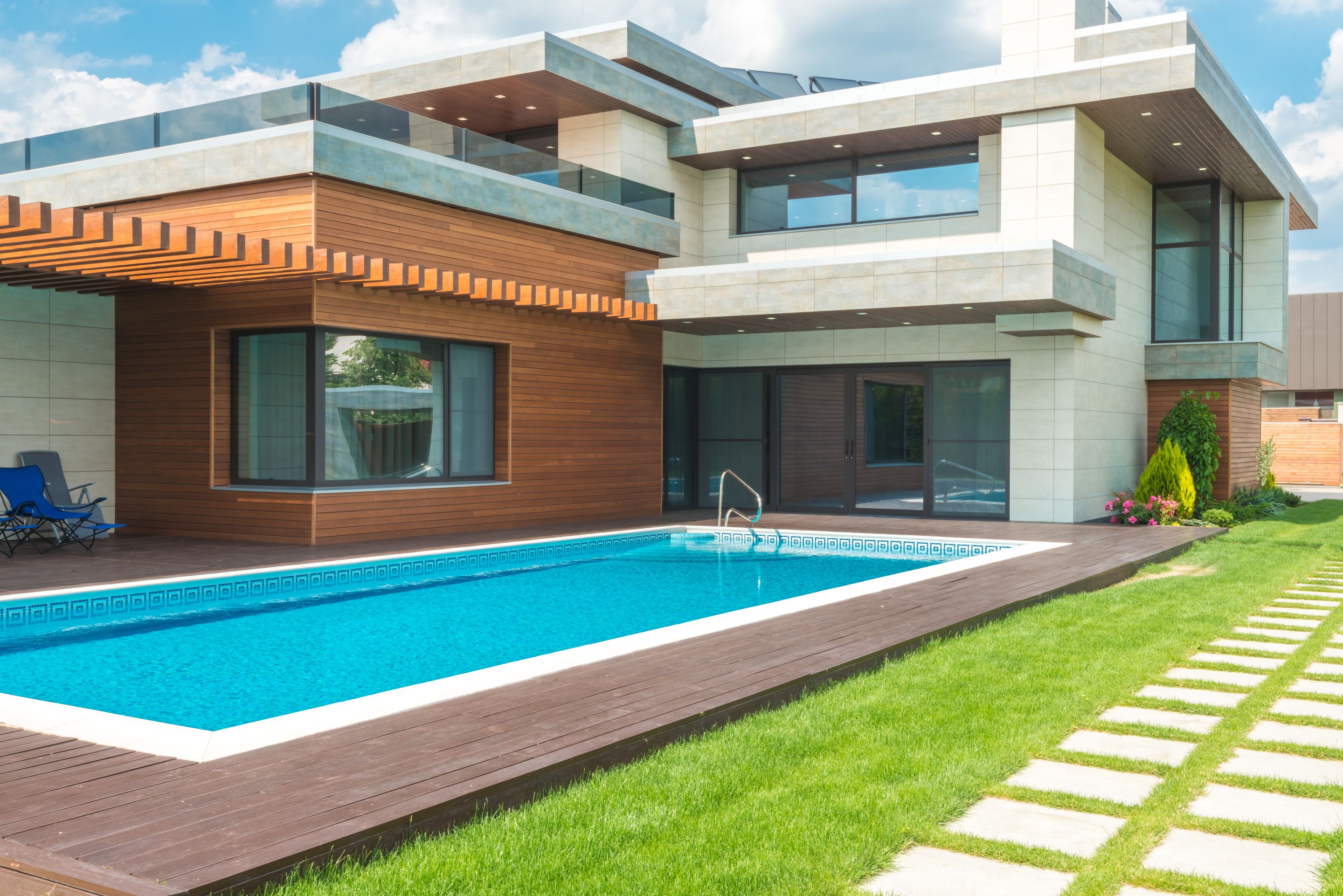 A modern house with a swimming pool, wood deck and clipped lawn