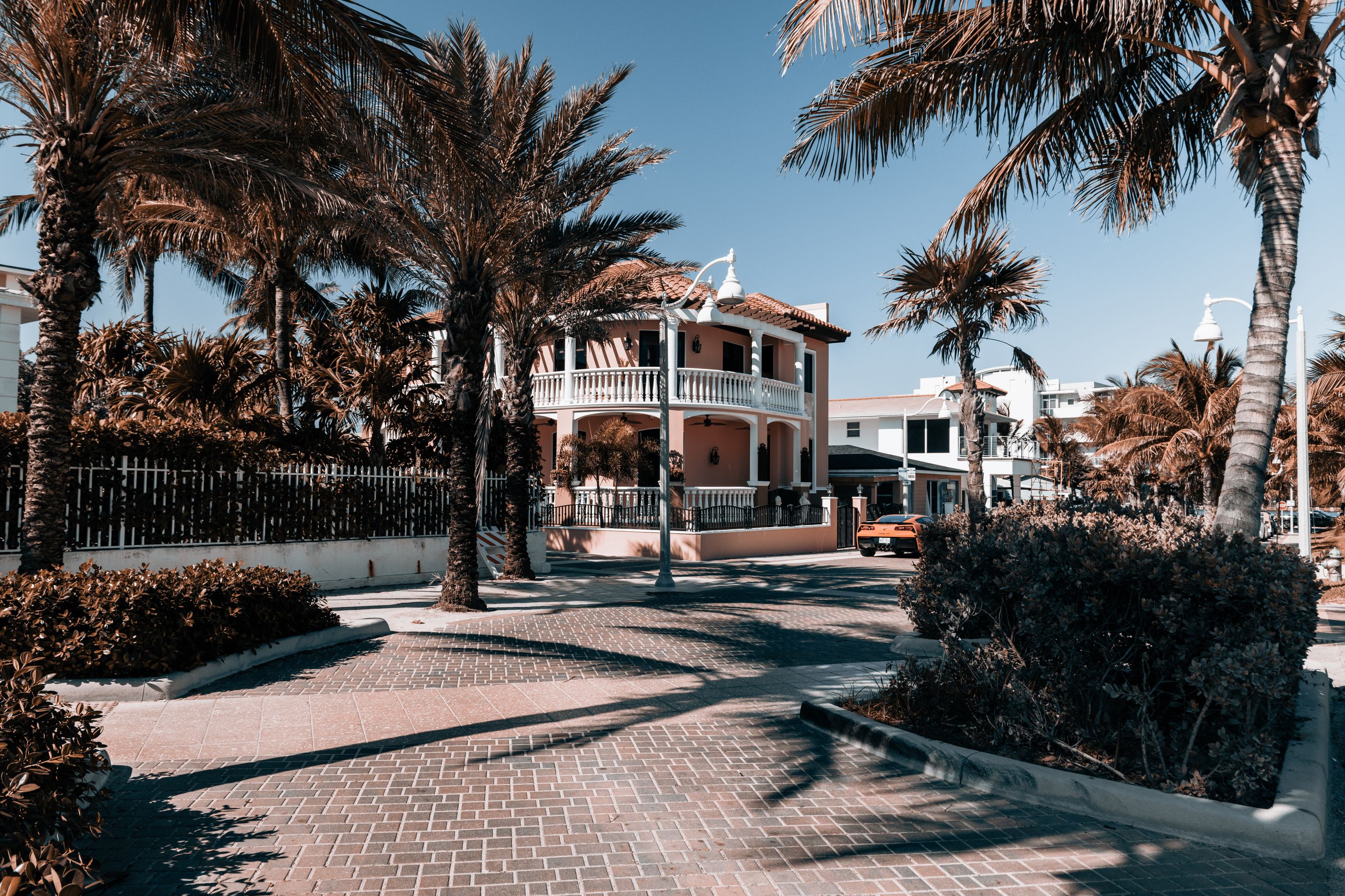 A two-story house with a wraparound porch framed by tall palms